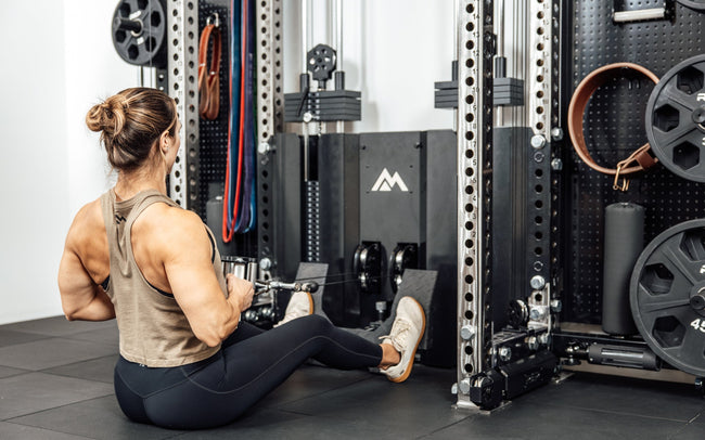 An athlete seated on the floor while performing a low cable row on the Wall-Mounted Ares™ 2.0